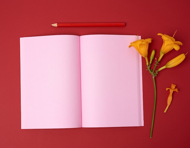 Öffnen Sie das Notizbuch mit leeren rosa Blättern und gelber Blume