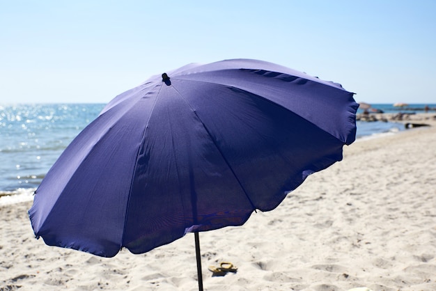 Öffnen Sie den blauen textilen Sonnenschirm am Meer