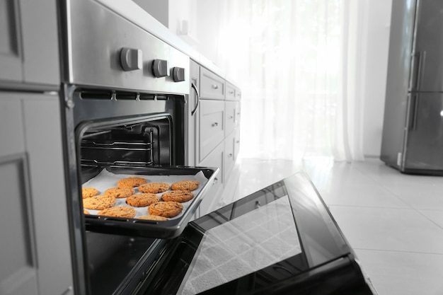 Öffnen Sie den Ofen mit leckeren hausgemachten Keksen in der Küche