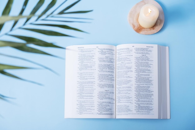 Öffnen Sie die Bibel mit Sandalen und Palmblättern auf blauem Hintergrund