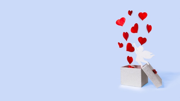 Öffnen Sie die silberne Geschenkbox mit fliegenden Herzen und Amor. Levitation. fröhlichen Valentinstag.