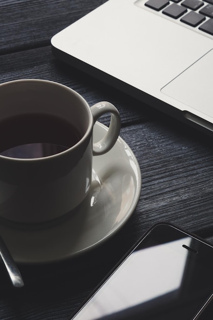 Öffnen Sie einen Laptop und eine Tasse Kaffee auf einer schwarzen Holzdeck-Nahaufnahme