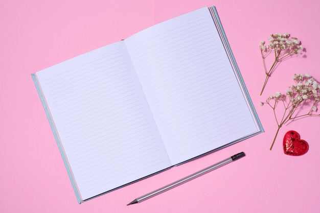 Öffnen Sie hölzernen Bleistift des Notizbuches auf Draufsicht des rosa Hintergrundes