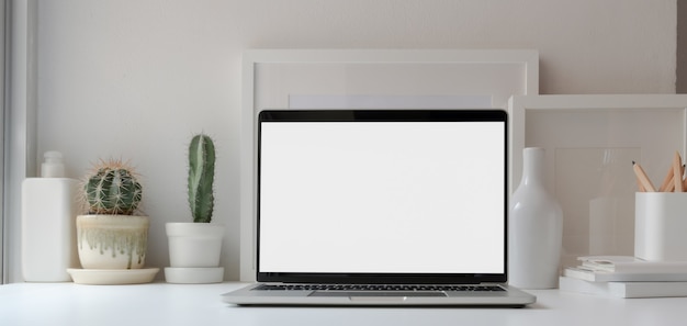Öffnen Sie Laptop-Computer des leeren Bildschirms im minimalen Arbeitsbereich mit Kaktustöpfen