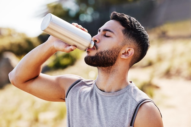 Ficar hidratado é como eu posso continuar foto de um jovem bonito sozinho do lado de fora e bebendo água durante sua corrida