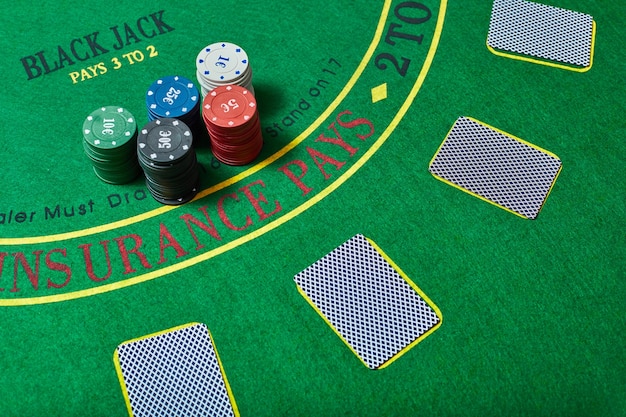 Fichas de casino y baraja de cartas en la mesa de casino verde, concepto de juego de póquer, vista superior.