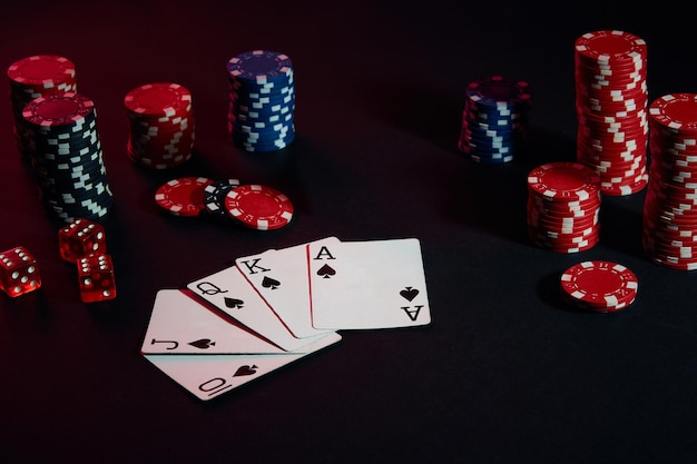 Fichas de casino y cartas sobre la superficie de la mesa negra. Concepto de juego, fortuna, juego y entretenimiento - cerrar