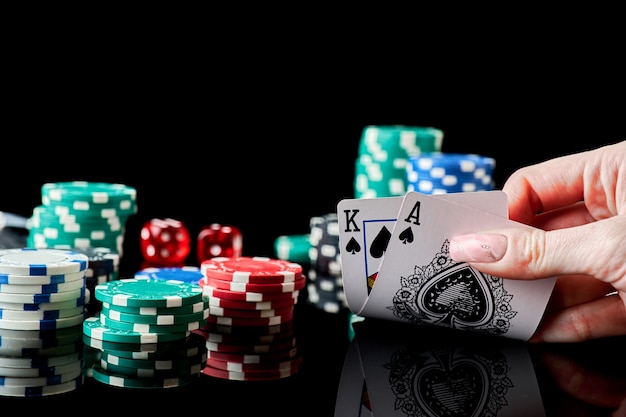 Fichas de casino jugando a las cartas y dados sobre fondo reflectante oscuro