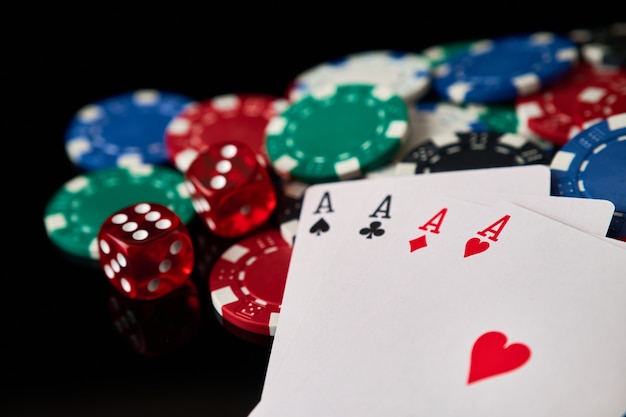 Fichas de casino jugando a las cartas y dados sobre fondo reflectante oscuro