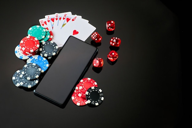 Fichas de casino jugando a las cartas dados y teléfono móvil en el cuadro negro