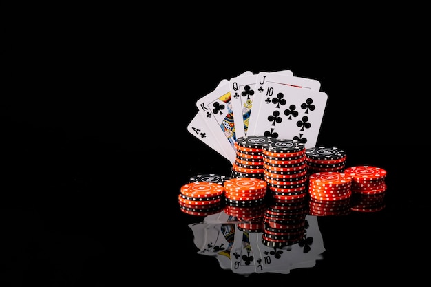 Fichas de poker e royal flush clube em fundo preto reflexivo