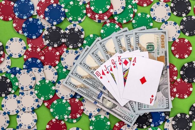 Fichas de pôquer com cartas e dólares na mesa.