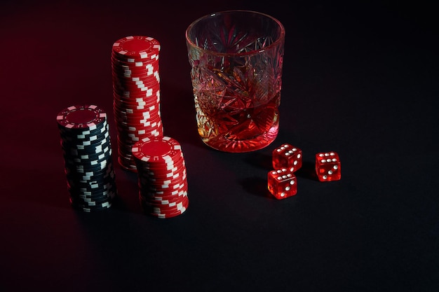 Fichas de pôquer e uma taça de vinho de conhaque na mesa escura. ainda vida. o conceito de jogo. poker online