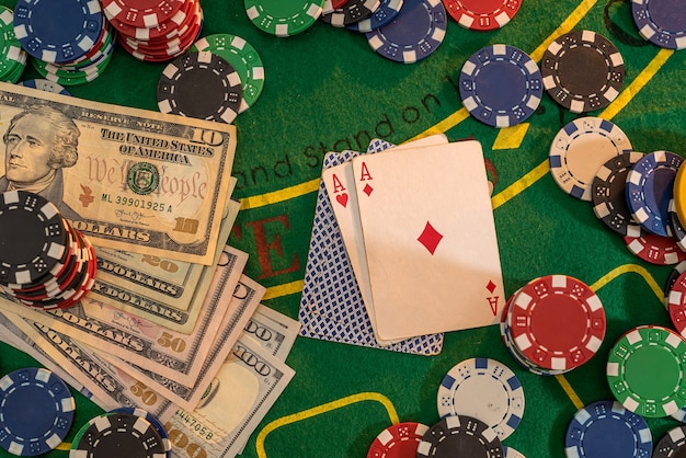 Fichas de juego de póquer con tarjetas y billetes de dólar en una mesa de casino verde. Apuestas online. Texas