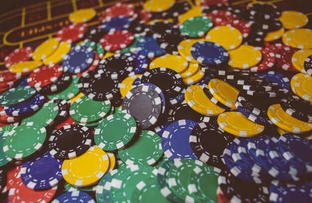 Las fichas de póquer coloridas del casino se encuentran en la mesa de juego en el procesamiento de fotos antiguas de la pila