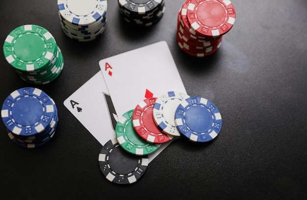fichas de póquer en una mesa negra con fichas de póquer blancas en el fondo.