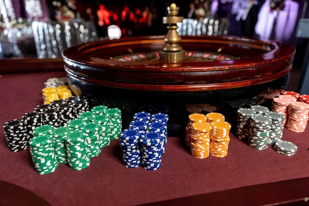 Fichas de primer plano y ruleta en el casino en la mesa roja.