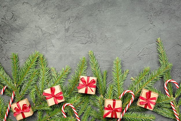 Fichtenzweige, Geschenke und Zuckerstange auf grauem Betonhintergrund