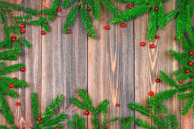 Fichtenzweige mit roten Beeren auf einem Holztisch kopieren Raum