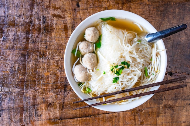 Foto fideos y albóndigas en un recipiente en una mesa de madera