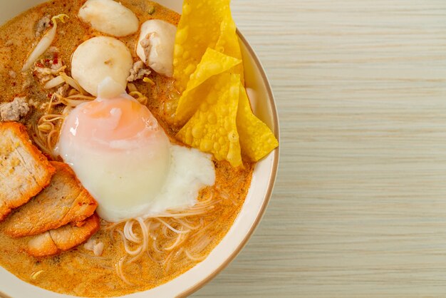 Fideos de arroz con albóndigas, cerdo asado y huevo en sopa picante