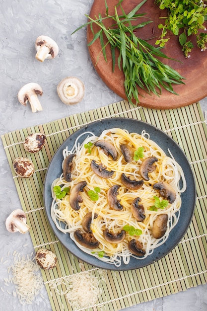 Fideos de arroz con champiñones champiñones, salsa de huevo y orégano sobre un fondo de hormigón gris. Vista superior.