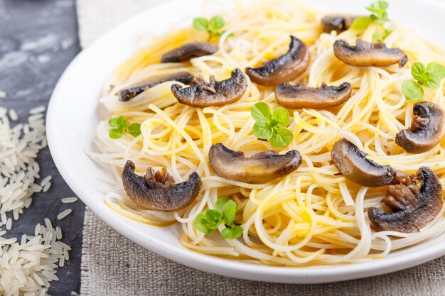 Fideos de arroz con champiñones champiñones sobre un hormigón negro.