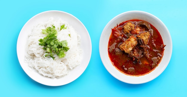 Fideos de arroz con curry de cerdo del norte de Tailandia sobre fondo azul.