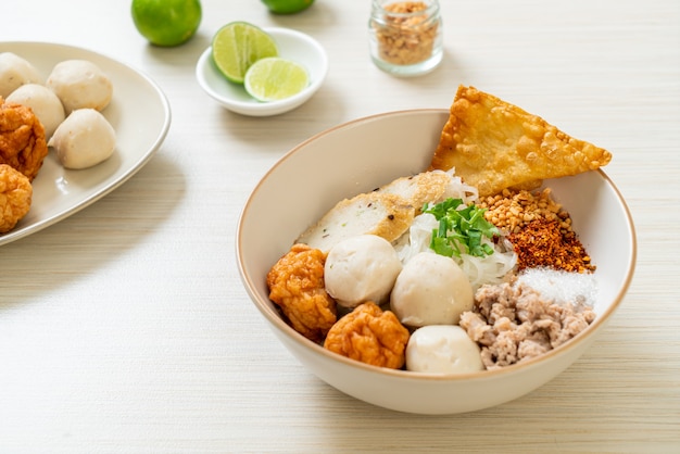 Fideos de arroz planos pequeños picantes con bolas de pescado y bolas de camarones sin sopa - estilo de comida asiática