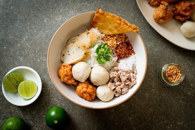 Fideos de arroz planos pequeños picantes con bolas de pescado y bolas de camarones sin sopa