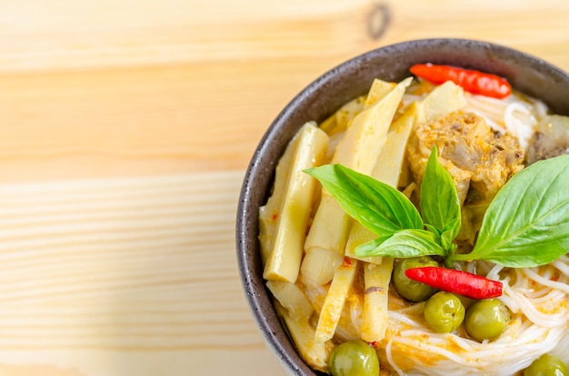 Fideos de arroz en salsa de pollo al curry con verduras sobre fondo de madera