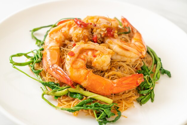 Fideos de arroz salteados y mimosa de agua con camarones en un plato