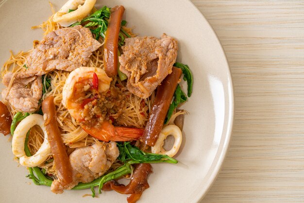 Fideos de arroz salteados y mimosa de agua con carne mixta - estilo de comida asiática