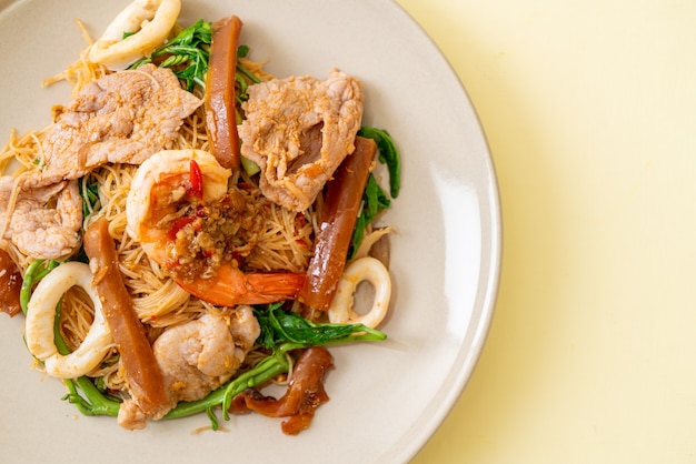 Fideos de arroz salteados y mimosa de agua con carne mixta - estilo de comida asiática