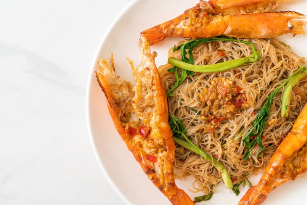 Fideos de arroz salteados y mimosa de agua con gambas de río en plato