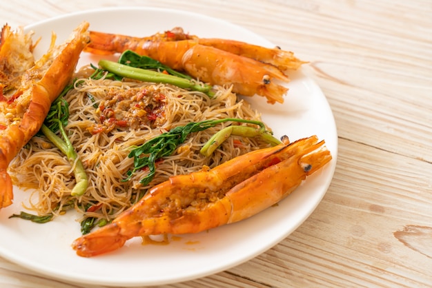 Fideos de arroz salteados y mimosa de agua con gambas de río en plato