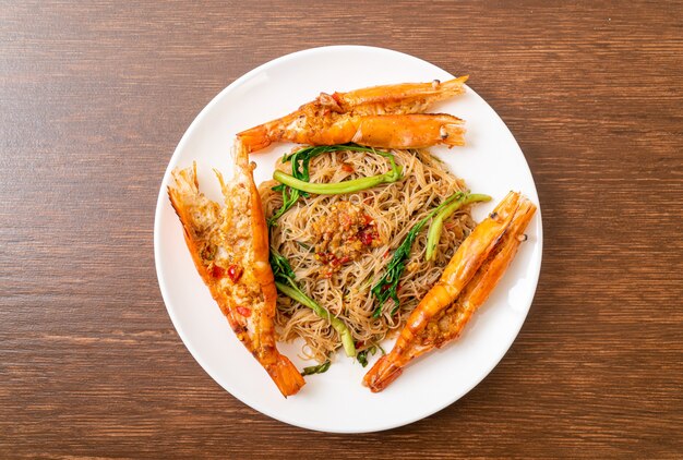 Fideos de arroz salteados y mimosa de agua con gambas de río en plato