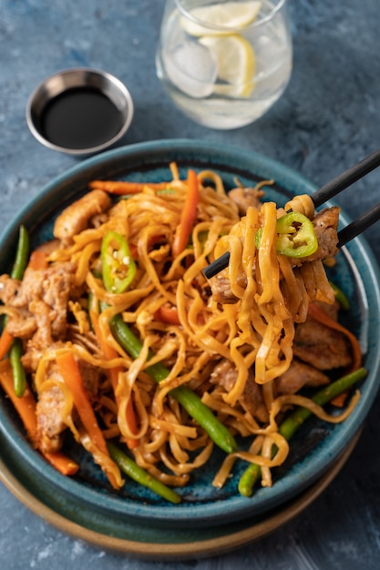 Fideos asiáticos con carne de cerdo en salsa teriyaki, con judías verdes, zanahorias y champiñones shiitake.