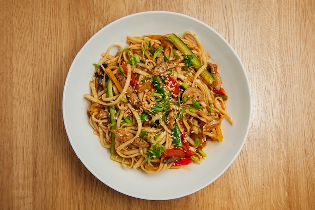 Fideos asiáticos con carne y verduras en plato blanco