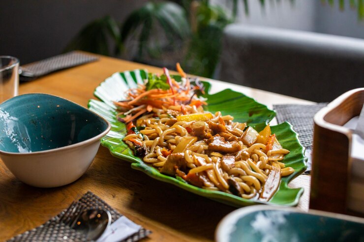 Fideos asiáticos de trigo soba udon con pollo y verduras en plato verde
