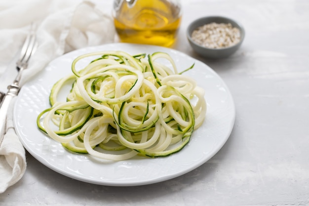 Fideos de calabacín en espiral en un plato blanco sobre fondo de cerámica