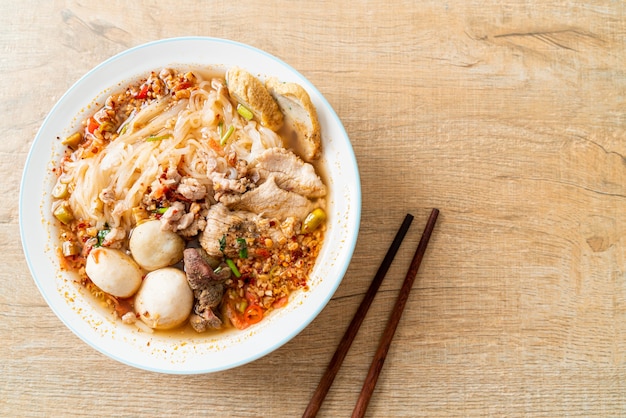 Fideos con carne de cerdo y albóndigas en sopa picante o fideos Tom yum al estilo asiático