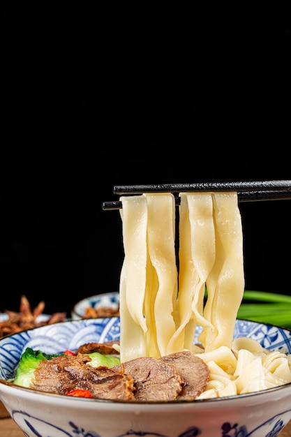 Foto fideos de carne de res sopa roja picante en un recipiente sobre la mesa de madera