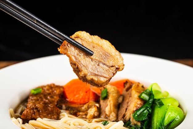 Fideos de carne de res sopa roja picante en un recipiente sobre la mesa de madera