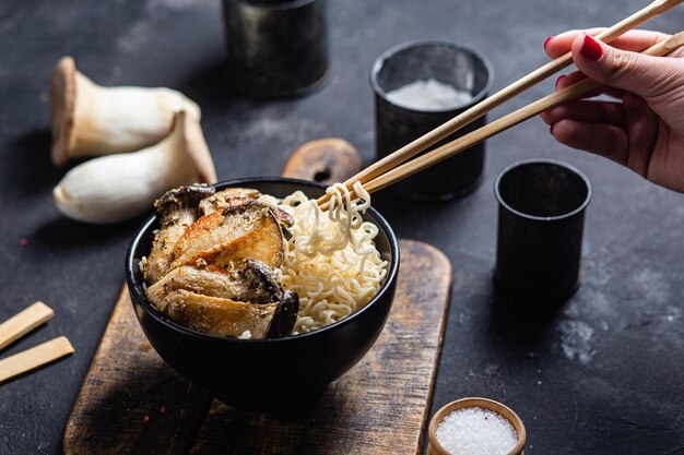 Fideos con champiñones eringi en un plato negro