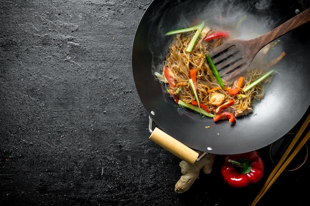 Fideos chinos de celofán al wok caliente en una sartén con una espátula