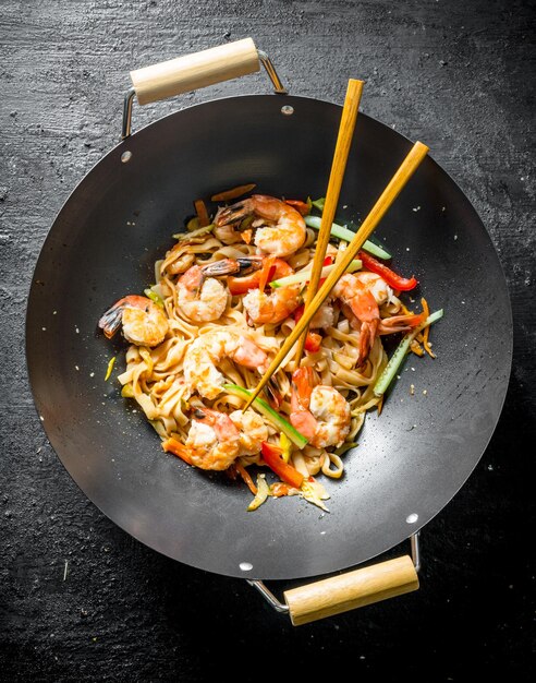 Fideos chinos Udon en una sartén wok con palillos