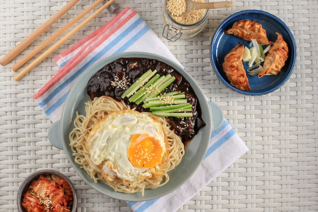 Fideos coreanos Jajang Myeon o JJajangmyeon con salsa de frijoles negros, servidos con pepino y semillas de sésamo