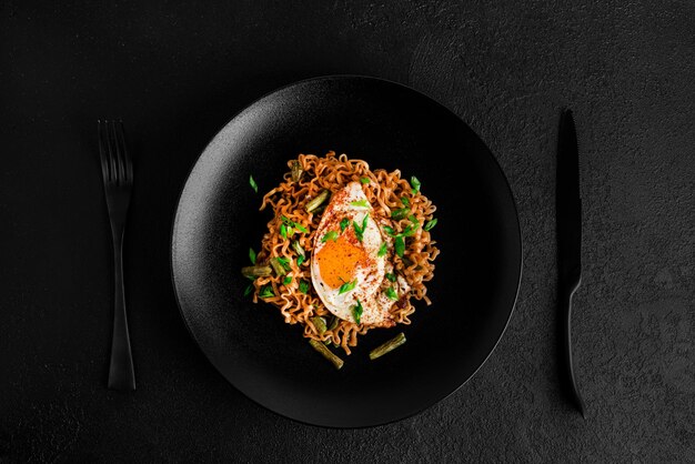 Fideos frescos calientes con fondo oscuro de huevo frito. foto de alta calidad