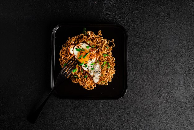 Fideos frescos calientes con fondo oscuro de huevo frito. foto de alta calidad